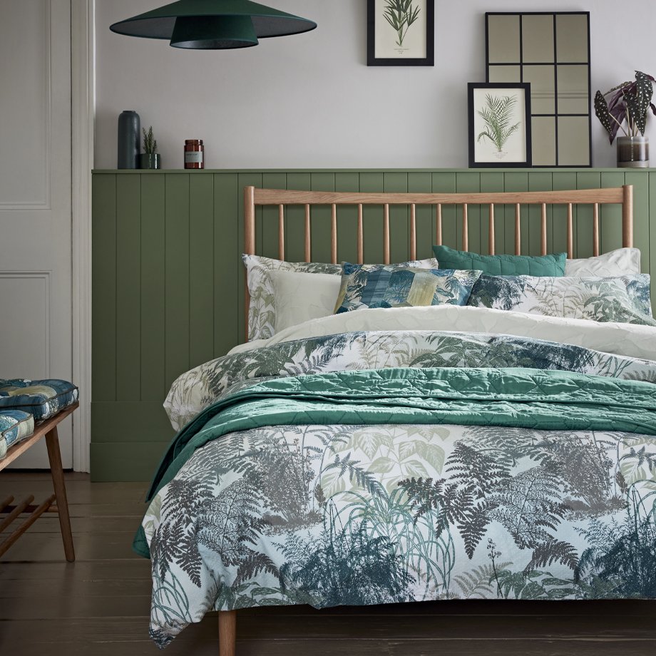 Green leaf bedding on a wooden bed frame.